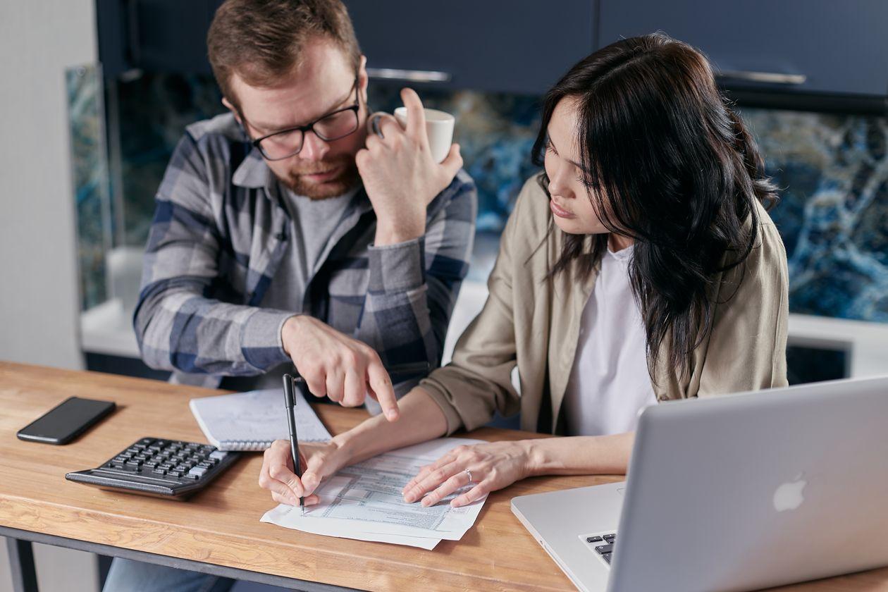 Couple reviewing tax forms with a calculator and laptop at home